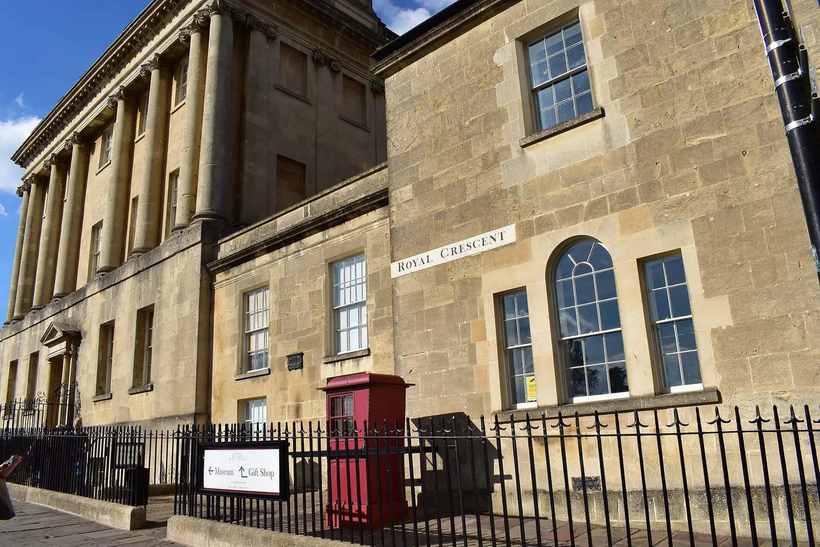 The curve of the Royal Crescent in Bath, England, golden stone under a clear sky.